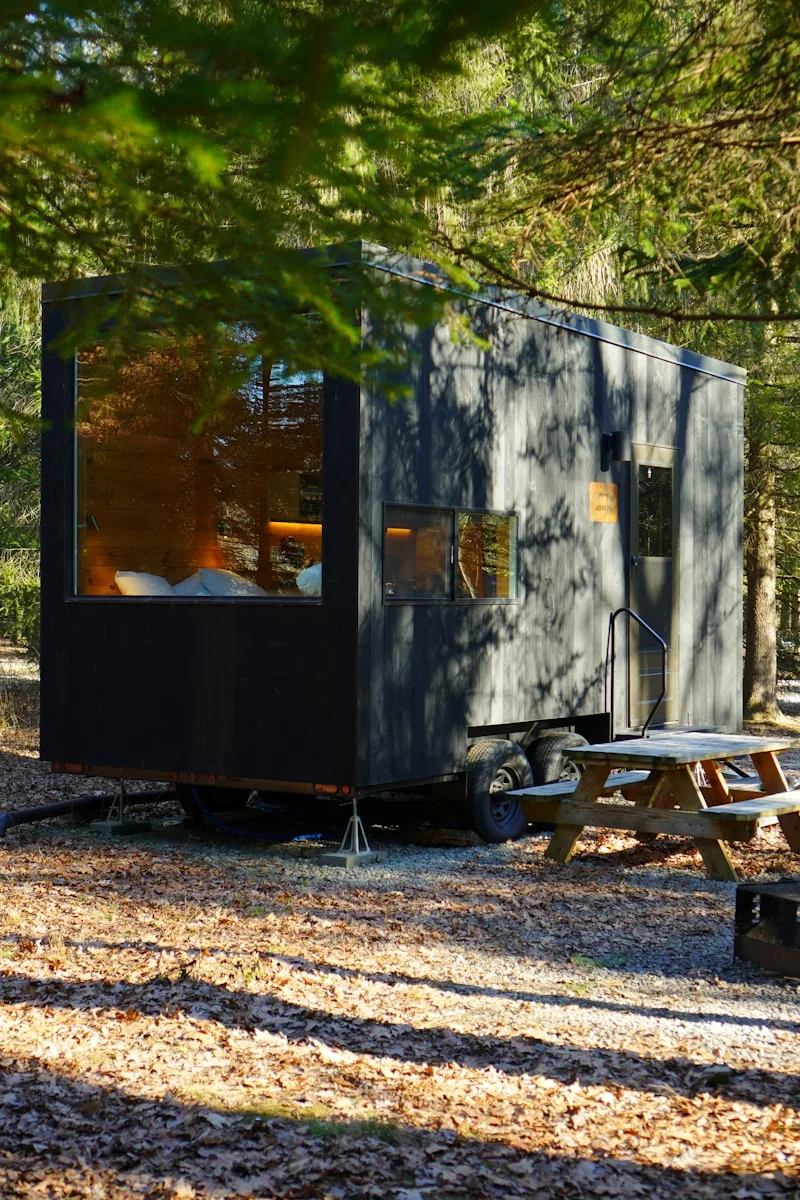 a tiny house in the woods with a picnic table